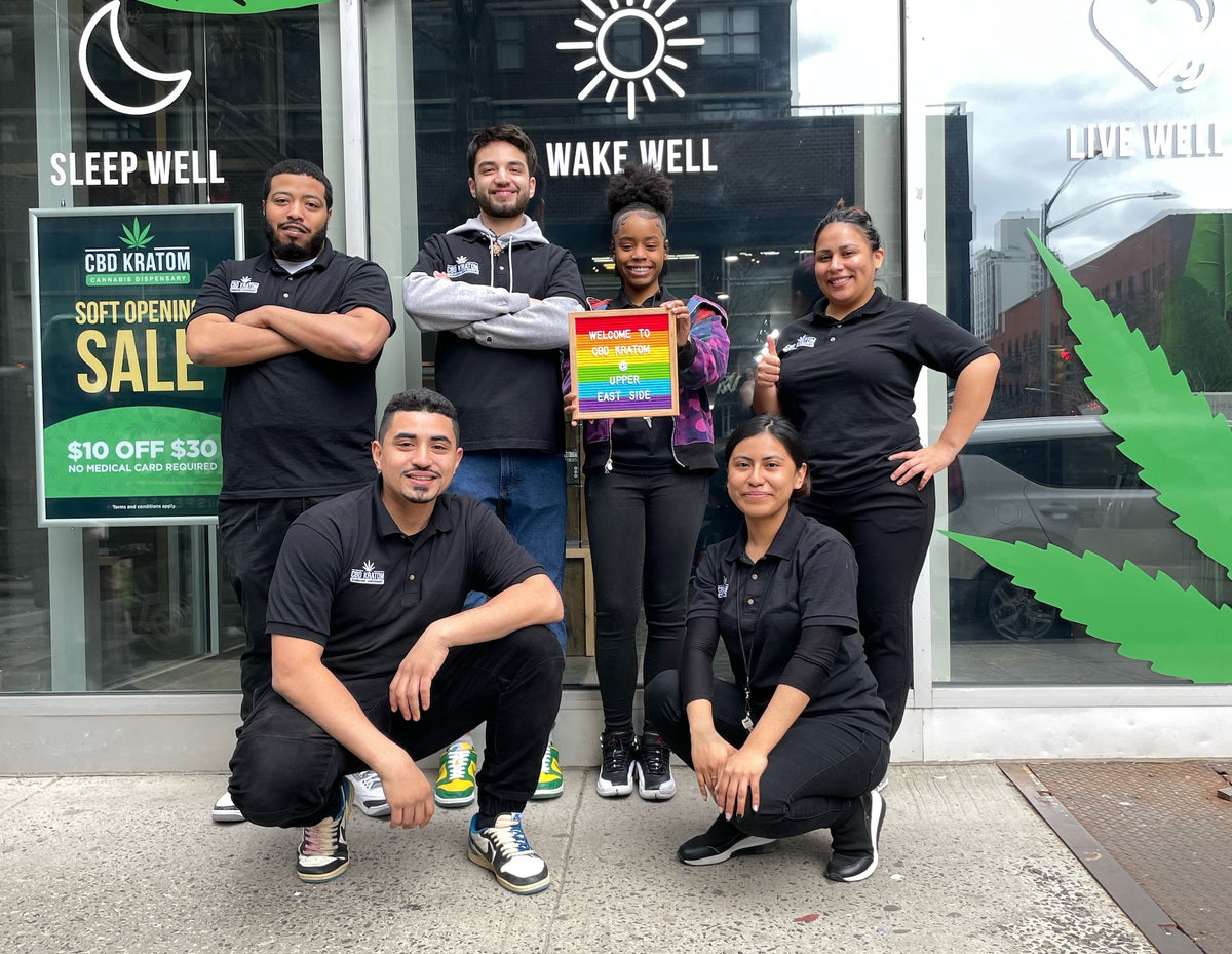 Six CBD Kratom team members outside the Upper East Side store in New York City, one holding a welcome sign.