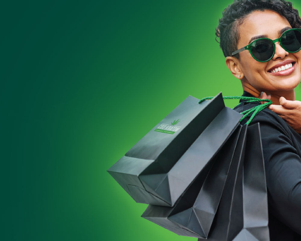 Smiling woman holding CBD Kratom shopping bags with green background promoting BOPIS Auto-Replenish & Save – skip shipping and save with in-store pickup subscriptions.