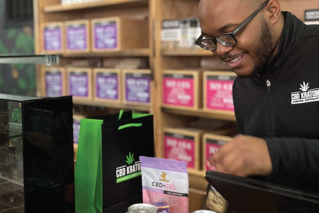 A CBD Kratom team member prepares an order at the counter.