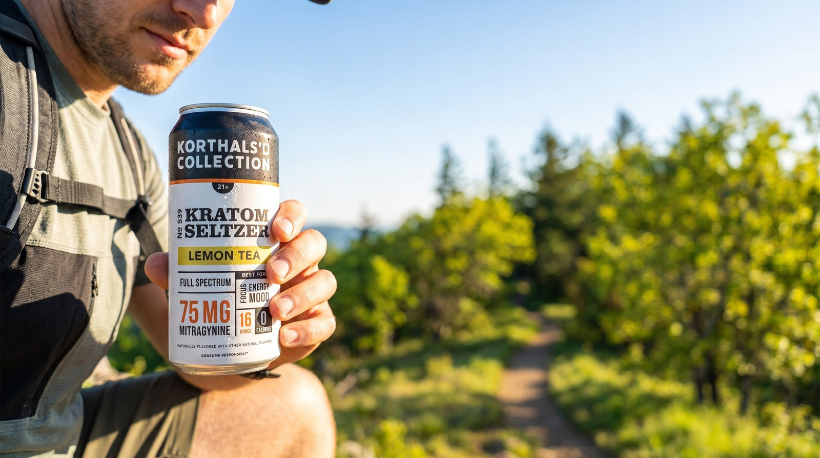 Hiker holding a No. 539 Lemon Kratom Seltzer can on a sunny trail