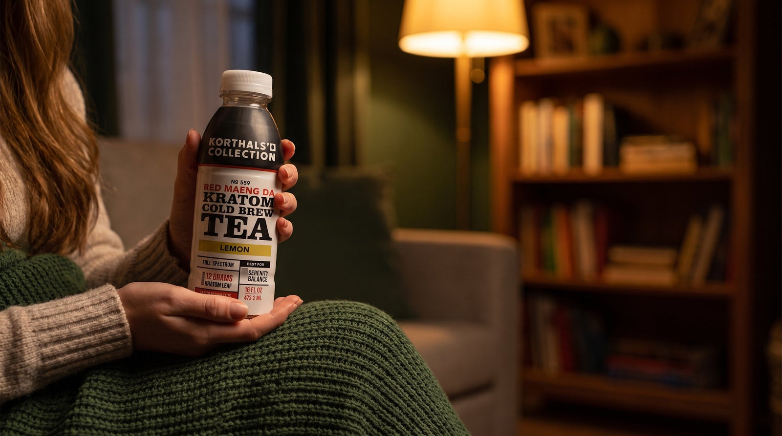 Woman cradling Korthals Collection Red Maeng Da cold brew tea in a cozy evening living room